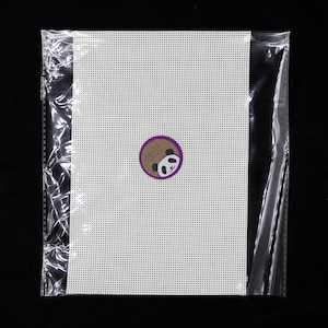 May include: A white plastic canvas sheet in a clear plastic bag. The canvas is for cross-stitch or needlepoint projects. A small round sticker with a panda bear logo is on the canvas.
