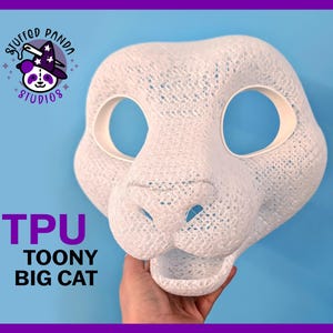 May include: A white TPU Toony Big Cat mask with large eye openings and a detailed nose and mouth. The mask is held against a blue background. The Stuffed Panda Studios logo is in the upper left corner.