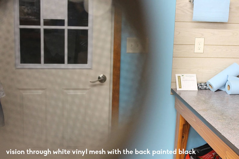May include: A white door with a window pane and a silver door handle. The door is seen through a white vinyl mesh with the back painted black.