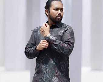 May include: A long-sleeved button-down shirt with a dark gray batik pattern. The shirt features a floral and paisley design in shades of gray, burgundy, and green. The text "TronicCraft" is visible on the shirt.