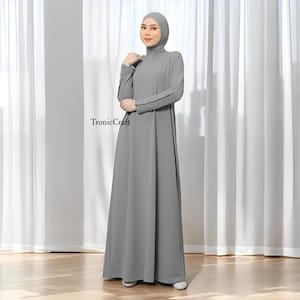 May include: A gray maxi dress with a high neck and long sleeves. The sleeves have pearl-like buttons on the cuffs. The dress has a loose, flowing fit.