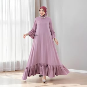 May include: A long, flowing mauve dress with a ruffled hem and bell sleeves. The dress has a high neckline and is worn with a matching mauve headscarf.
