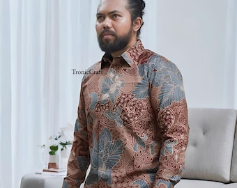 May include: A long-sleeved button-down shirt with a brown, blue, and tan floral batik pattern. The shirt has a classic collar and a pocket on the left chest. The brand name "TronicCraft" is printed on the shirt.