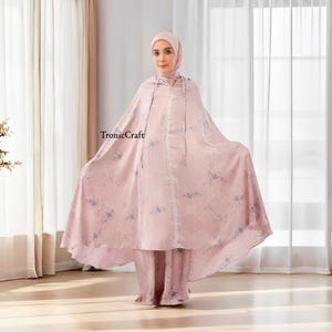 May include: A pink prayer robe with a floral pattern and a matching pair of pants. The robe has a hood and a long, flowing design.