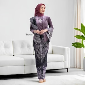 May include: A woman wearing a traditional purple outfit. The outfit includes a long-sleeved top, a patterned skirt, and a matching head covering. A patterned shawl is draped over the shoulders. The outfit is a formal style. The text "TronicCraft" is visible.
