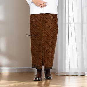 May include: A brown sarong with a diagonal patterned design. The sarong is worn with a white shirt and brown shoes. The text "TronicCraft" is visible on the sarong.