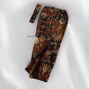 Op de afbeelding: Een broek van bruin en zwart met een gouden en bruin bloemenpatroon. De broek heeft een tailleband en is gemaakt van een zachte, zijdeachtige stof.