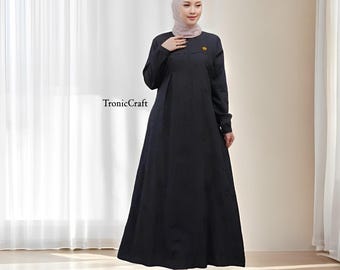 May include: A long, black dress with long sleeves and a flowing skirt. The dress has a small, gold-colored embellishment on the chest. The text "TronicCraft" is visible on the left side of the image. The person is wearing a head covering.