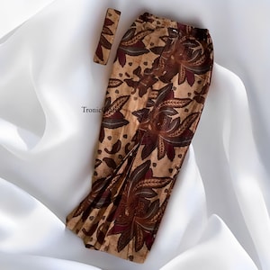 May include: A brown and beige skirt with a floral pattern. The skirt has a pleated hem and a waistband with a button closure.