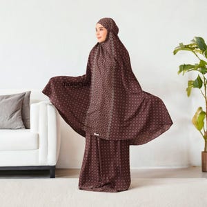 May include: A brown prayer outfit with a white geometric pattern. The outfit includes a long skirt and a matching top with a hood.