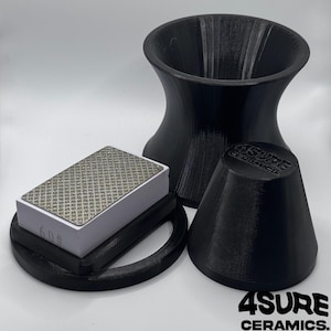 Puede incluir: Un embudo negro impreso en 3D, una tapa cónica negra con el relieve 4SURE CERAMICS y una piedra de afilar rectangular con superficie de patrón de diamante y marca 60# sobre una base blanca, dispuestos sobre un fondo blanco liso.
