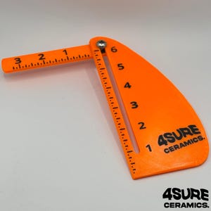Puede incluir: Herramienta de medición de cerámica naranja brillante con marcas negras y el texto "4SURE CERAMICS". La herramienta tiene un brazo articulado con medidas en pulgadas hasta 3 pulgadas (7.6 cm) y una sección curva hasta 6 pulgadas (15.2 cm).