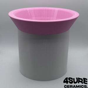 Puede incluir: Un recipiente cilíndrico con un cuerpo de color gris claro y un borde ancho y acampanado de color rosa. El objeto tiene un acabado liso y uniforme con un diseño bicolor. El texto 4SURE CERAMICS está impreso en negro en la esquina inferior derecha.