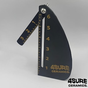 May include: Black ceramic tool with gold markings and the text "4SURE CERAMICS." The tool has a hinged arm with inch measurements from 1 to 3. The main body has inch measurements from 1 to 6. A screw secures the arm.
