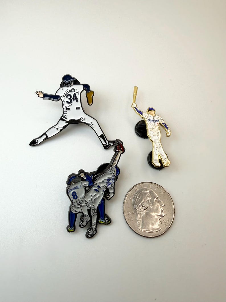 Pu&ograve; includere: Tre spille smaltate a tema baseball. Una spilla raffigura un lanciatore in uniforme bianca con il numero 34. Un'altra mostra un battitore in uniforme bianca e blu. La terza spilla mostra due giocatori in uniforme blu. Una moneta &egrave; inclusa per la scala.