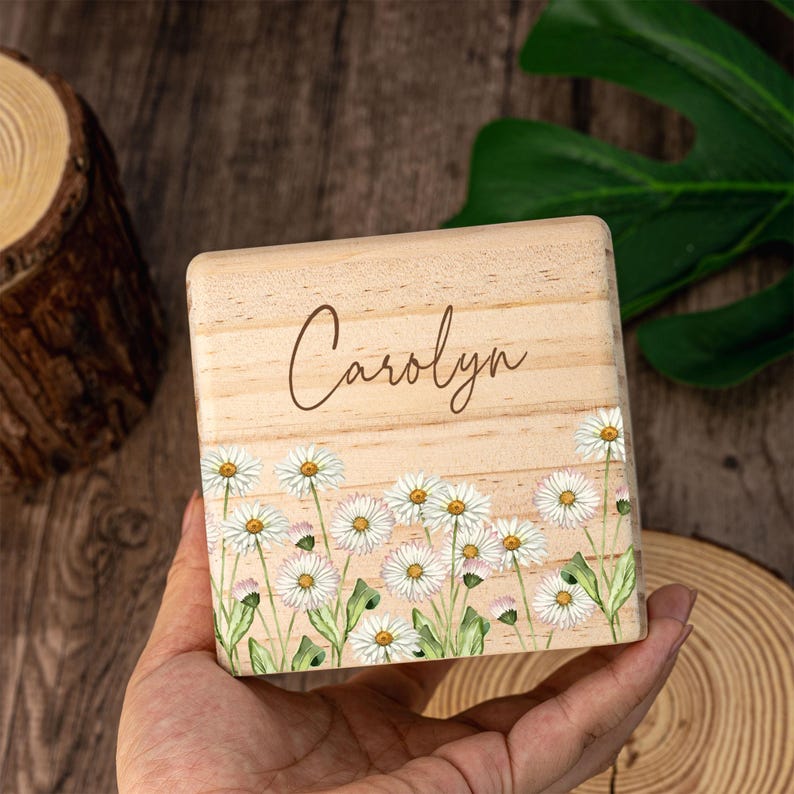 May include: A wooden box with a white daisy floral design and the name "Carolyn" engraved on the front.