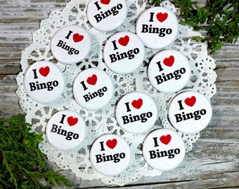 May include: Twelve 1 1/4 inch white round pinback buttons with a red heart and the text "I love Bingo" in black lettering.