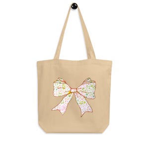 Die umweltfreundliche Einkaufstasche Coquette Bow ist ein perfektes Accessoire für jeden Anlass und bietet viel Platz für Lebensmittel, Bücher und Strandartikel.