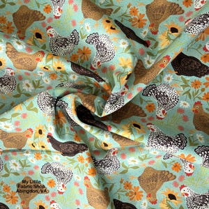 May include: Fabric with a repeating pattern of chickens in various colors, including brown, black, and white, set against a light blue background with orange and white flowers. The text "My Little Fabric Shop Abingdon, VA" is visible.