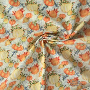 Puede incluir: Tela con un estampado repetido de calabazas naranjas y amarillas, calabazas y hojas sobre un fondo claro. Las calabazas tienen tallos verdes y están rodeadas de follaje azul y verde. Ideal para manualidades con temática otoñal.