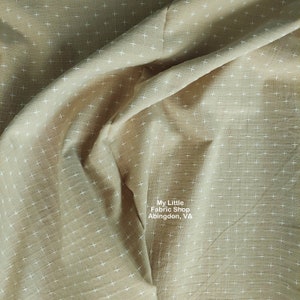 Könnte beinhalten: Beigefarbener Stoff mit einem weißen Kreuzmuster. Der Stoff ist gefaltet und der Text "My Little Fabric Shop Abingdon, VA" ist in der rechten unteren Ecke sichtbar.
