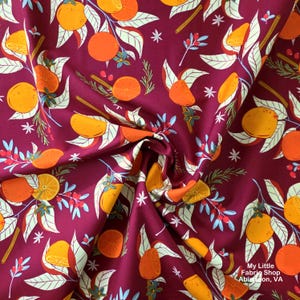 May include: A deep burgundy fabric featuring a repeating pattern of bright orange citrus fruits, green leaves, sprigs of rosemary, red berries, and small white star shapes. The text My Little Fabric Shop Abingdon, VA is printed in white.