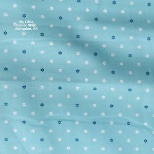 May include: Light blue fabric with a repeating pattern of small white and navy blue floral designs. The fabric has a slightly textured appearance. The text "My Little Fabric Shop Abingdon, VA" is in the upper left corner.