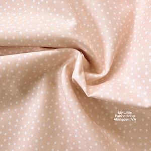 Puede incluir: Primer plano de una tela color melocotón con un patrón repetido de pequeños lunares blancos. La tela está arrugada y doblada, mostrando la textura y la caída del material. La tela es de My Little Fabric Shop, Abingdon, VA.