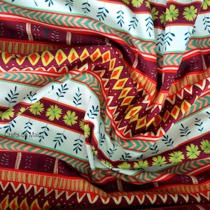 Puede incluir: Tela blanca con un patrón geométrico colorido. El patrón incluye rayas rojas, naranjas, amarillas, verdes y azules con un diseño repetitivo de flores y hojas. El texto "Crafts on Main" es visible en la esquina inferior izquierda de la imagen.