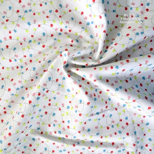 Puede incluir: Tela blanca con un patrón repetido de luces navideñas de colores. Las luces son rojas, azules, amarillas y rosas, conectadas por finas líneas grises. La tela tiene una textura suave y ligeramente arrugada. Texto: "My Little Fabric Shop Abingdon, VA."