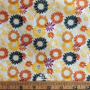 May include: White fabric with a repeating pattern of yellow, orange, red, and dark green stylized flowers. The fabric is measured with a ruler in inches.