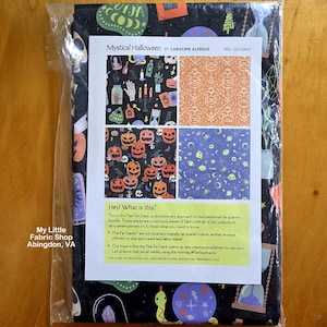 May include: A folded fabric bundle titled Mystical Halloween by Caroline Alfreds in a clear plastic bag. The fabric features black, orange, and purple patterns of pumpkins, skulls, hourglasses, and celestial motifs. A white information sheet is attached.