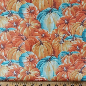 Puede incluir: Tela con un patrón repetido de calabazas en tonos naranja, turquesa y amarillo. Las calabazas tienen tallos marrones oscuros. El texto "My Little Fabric Shop Abingdon, VA" es visible. Ideal para manualidades con temática otoñal.