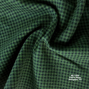 Pode incluir: Close-up de um tecido xadrez verde e preto. O tecido tem uma aparência texturizada com um pequeno padrão quadrado. O tecido está drapeado, mostrando dobras e sombras. O tecido é da My Little Fabric Shop, Abingdon, VA.