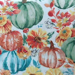 Puede incluir: Una tela blanca con un patrón floral que presenta calabazas, flores y hojas. Las calabazas son verdes, naranjas y azules. Las flores son amarillas, naranjas y rojas. Las hojas son verdes.