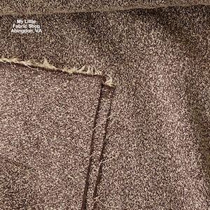 May include: Close-up of a textured fabric in a deep burgundy color with flecks of white. The fabric is folded, revealing a raw edge with frayed threads. The text "My Little Fabric Shop Abingdon, VA" is visible in the upper left corner.