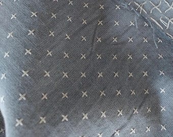 May include: A close-up of a gray fabric with a white cross pattern. The fabric has a subtle texture and a slightly faded appearance.