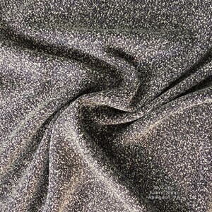 May include: Close-up of a textured fabric with a speckled pattern in shades of dark gray and white. The fabric is draped, showing folds and shadows. The fabric is from My Little Fabric Shop, Abingdon, VA.