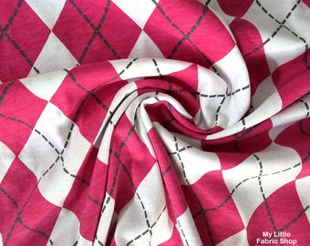 May include: Pink and white argyle fabric with black stitching details. The fabric is folded, showing the pattern's repeating diamond shapes. The fabric is from My Little Fabric Shop, Abingdon, VA.