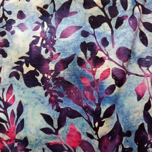 Puede incluir: Tela batik abstracta con fondo azul y un patrón de hojas de color morado oscuro y rosa.