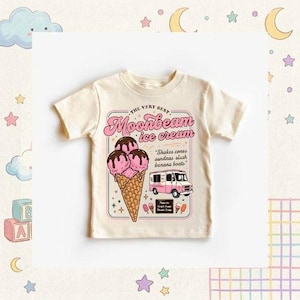 May include: Cream-colored t-shirt featuring a retro ice cream design. The graphic includes the text "THE VERY BEST Moonbeam ice cream" with an illustration of ice cream cones, a truck, and the text "Shakes cones sundaas slush banana boats."
