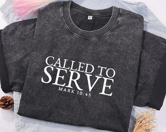 Può includere: Una maglietta nera con una stampa bianca usurata che dice "Called to Serve" e "Mark 10:45".