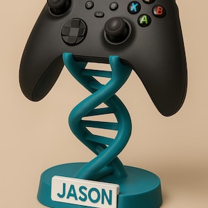 May include: Black Xbox controller resting on a teal DNA-shaped stand. The stand has a teal base with the name "JASON" on a white rectangular plate. The controller has colored buttons and a black finish.