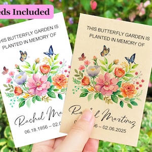 Könnte beinhalten: Zwei rechteckige Samentütchen mit einem Aquarell-Blumenmotiv und Schmetterlingen. Die weißen und beigen Tütchen zeigen den Text THIS BUTTERFLY GARDEN IS PLANTED IN MEMORY OF, den Namen Rachel Martinez und die Daten 06.18.1956 – 02.06.2025.