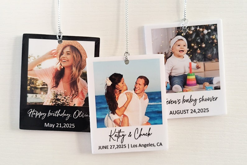 May include: Three white photo ornaments with black borders and text. The top ornament features a baby sitting in front of a Christmas tree. The text reads "even's baby shower AUGUST 24, 2025". The middle ornament features a couple on a beach. The text reads "Kathy & Chuck JUNE 27, 2025 | Los Angeles, CA". The bottom ornament features a woman in a pink shirt and straw hat. The text reads "Happy birthday. Olivia May 21, 2025".