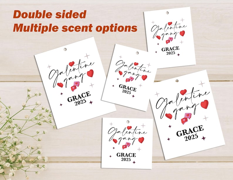 May include: Several white tags with the words "Galentine gang" in a script font, red hearts, and "GRACE 2025". The tags have a small hole at the top and are displayed on a light wood surface. The text "Double sided" and "Multiple scent options" are also visible.