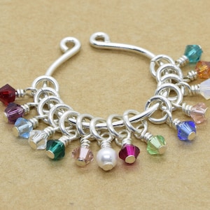 May include: A silver septum ring with a chain of small, colourful crystal beads hanging from it.