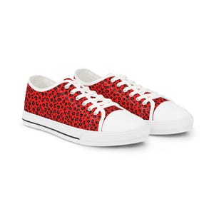 May include: Red canvas trainers featuring a black leopard print design. The shoes have white laces, white rubber toe caps, and white soles with a black stripe.