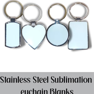 May include: Four stainless steel keychain blanks in various shapes: a rectangle, a heart, a circle, and a smaller rectangle. Each blank has a silver-colored metal frame and a silver key ring. The text "Stainless Steel Sublimation Keychain Blanks" is below the keychains.