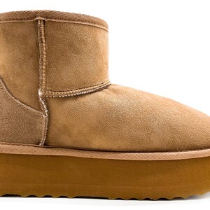 Puede incluir: Botas de invierno de gamuza marrón con una suela gruesa de goma marrón.